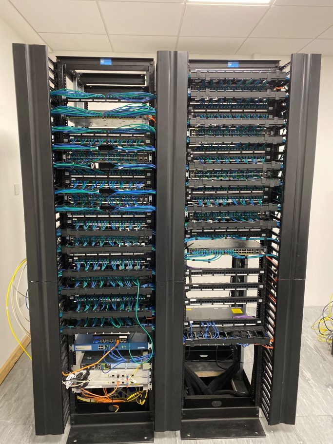 Two server racks filled with networking equipment and cables.